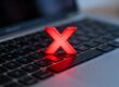 Laptop keyboard with a red cross symbol over it.