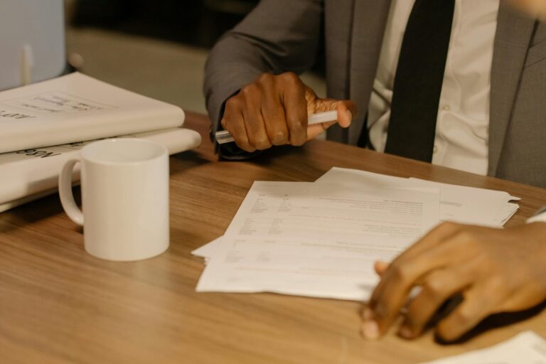 pexels-cottonbro-8369207-scaled.jpg Free Close-up of a businessman holding and reviewing documents on a wooden desk. Stock Photo